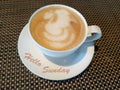 Hello Sunday greetings with a white cup of coffee and natural mat pattern background