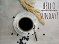 Hello Sunday. Text welcoming Sunday with background of a cup of blank morning coffee, spoon, roasted coffee beans decoration. Royalty Free Stock Photo