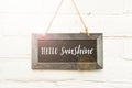 Hello sunshine welcome text on chalkboard hanging on white brick