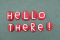 Hello there, creative message composed with red colored stone letters over green sand Royalty Free Stock Photo