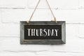 Hello thursday text on hanging board white brick ourdoor wall