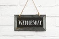 Hello wednesday text on hanging board white brick stones wall Royalty Free Stock Photo