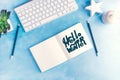 Hello winter graphic handlettering in Open notebook with keyboard on blue table top view flat lay mock up