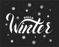 Hello winter text. Brush lettering at blue winter background with snowflakes and bokeh lights Royalty Free Stock Photo