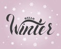 Hello winter text. Brush lettering at blue winter background with snowflakes and bokeh lights Royalty Free Stock Photo