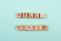 Hello winter word written on wood block. Greeting card concept on mint background. Flat lay studio shot.