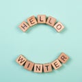 Hello winter word written on wood block. Greeting card concept on mint background. Flat lay studio shot.