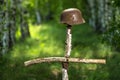 Helmet on the birch cross. The grave of an unknown German soldier in the forest. Imitation. WW2 recovery. Royalty Free Stock Photo