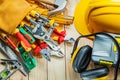 Helmet construction tools in tool belt and toolbox with earphones on wood boards