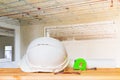 helmet plastic white with glasses, paper roll plan blueprint and measuring tape green on wood table in interior Construction site