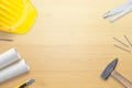 Helmet, tools and plans on wooden work desk. Copy space in the middle