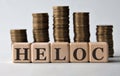 HELOC - acronym on wooden cubes on the background of stacks of coins Royalty Free Stock Photo