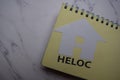 HELOC write on sticky note and house made from paper isolated on Office Desk Royalty Free Stock Photo