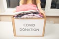 Help with coronavirus covid 19. A volunteer girl at a charity center holds a box of donation clothing Royalty Free Stock Photo