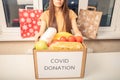 Help with coronavirus covid 19. A volunteer girl at a charity center holds a box of donation food products Royalty Free Stock Photo