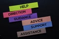 Help, Direction, Guidance, Advice, Support, Advice, Assistance text on sticky notes on Black desk. Mechanism Strategy