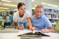 Help the elderly in the public library. Young volunteers help elderly Royalty Free Stock Photo