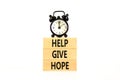 Help give hope symbol. Concept word Help give hope on beautiful wooden block. Black alarm clock. Beautiful white table white Royalty Free Stock Photo