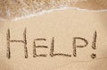 Help handwritten on sand of beach