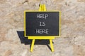 Help is here and support symbol. Concept words Help is here on black chalk blackboard on a beautiful stone background. Business,