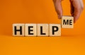 Help me symbol. Businessman holds wooden cubes with words help me. Beautiful orange background, copy space. Business, motivational