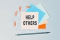 Help Others - text on sticky note paper on gray background. Closeup of a personal agenda. Top view Royalty Free Stock Photo