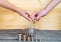 Help save money for the future. The two hands drop the coin into the savings glass, Close up hand putting coins in the stack on a