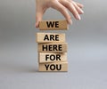 Help symbol. Wooden blocks with words We are here for you. Beautiful grey background. Businessman hand. Business and 'We are Royalty Free Stock Photo