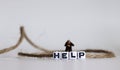A HELP text alphabet cube in a rope. Miniature people.