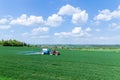 With the help of a tractor, wheat is sprayed with fertilizers or herbicides in rural areas.