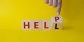 Help vs Hell symbol. Businessman hand points at turned wooden cube with words Hell and Help. Beautiful yellow background.