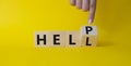 Help vs Hell symbol. Businessman hand points at turned wooden cube with words Hell and Help. Beautiful yellow background.