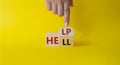 Help vs Hell symbol. Businessman hand points at turned wooden cubes with words Hell and Help. Beautiful yellow background.