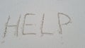 Help written on sandy beach by sea or ocean Royalty Free Stock Photo