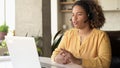 Helpful biracial woman wearing headset using laptop computer for video connection