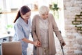 Helpful caregiver assisting woman with crutches