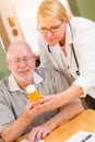 Helpful Doctor or Nurse Explaining Prescription Medicine to Attentive Senior Man Royalty Free Stock Photo