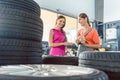 Helpful female auto mechanic checking the identification number of a tire