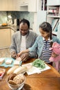 Cute girl feeling joyful while helping father making sandwiches