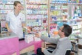 Helpful pharmacist serving disable man in pharmacy Royalty Free Stock Photo