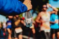 A helping hand delivers a bottle of water to a runner in a running race for him to drink