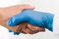 Helping hand of health professional holding old wrinkly palm on white background