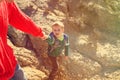 Helping hand- little boy helped by parent in mountains Royalty Free Stock Photo