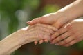 Young caregiver holding seniors hands. Helping hands, care for the elderly concept