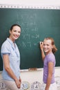 Helping her reach her potential. A young girl doing her sums on the blackboard while her teacher supervises.