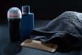 Closeup of men\'s toilet accessories. A deodorant, an Eau de toilette fragrance bottle, a beard brush, and a towel.