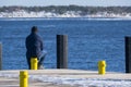 An alone man sitting on a yellow bollard looking at the frozen sea