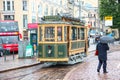 Helsinki, Finland - Jun 12 2014, Vintage sightseeing tourist tram in the city center and the pedestrian with umbrella in the rain