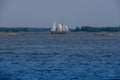 An Old Two-masted Wooden Schooner Sailing Across The Horizon Between Two Skerries