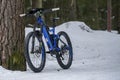 Helsinki, Finland - March 13, 2019: Electric mountain bike standing against tree on snowy ground in Helsinki